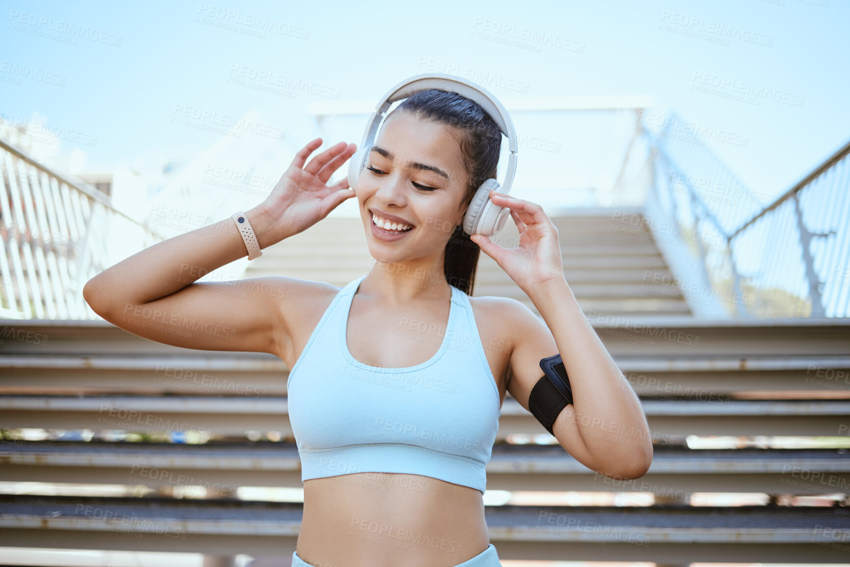 Buy stock photo Fitness, music and black woman training on the city stairs in Singapore for a marathon competition. Young, happy and smile athlete runner with motivation for cardio workout from audio on headphones