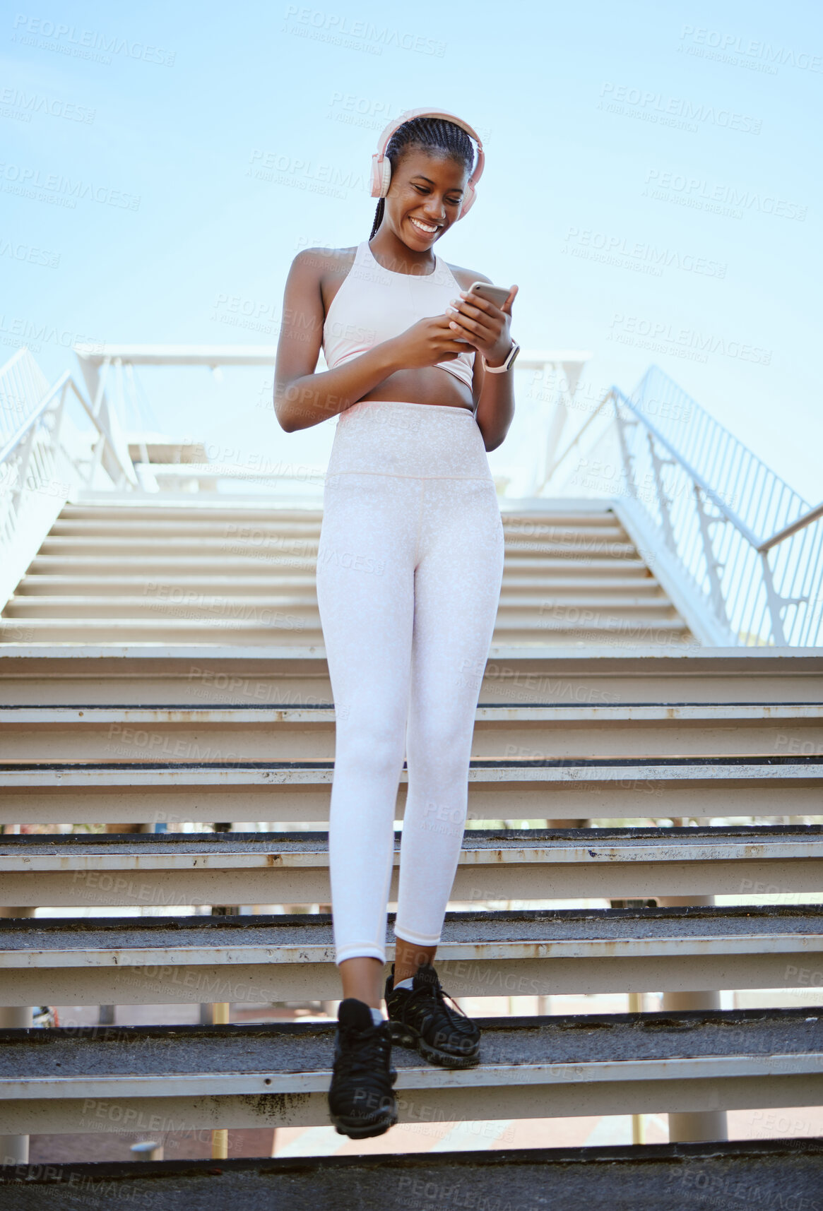 Buy stock photo Smile, fitness and black woman on a phone for music, social media content and streaming podcast via headphones. Happy, city and young girl checking progress on a wellness or exercise app in Africa