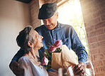 Love, flowers and gift of a senior couple in celebration of a birthday, anniversary or milestone. Elderly man and woman, happy, romantic and smiling together in a retirement home with champaign