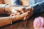 Macro, couple and hands of elderly people on table for support, love and care. Zoom, senior and hand together on desk with flower for bonding, anniversary and romance in marriage, life and retirement