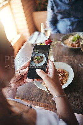 Buy stock photo Phone, food and social media with the hands of a woman taking a photograph while eating in a restaurant during a date. Mobile, internet and romance with a female snapping a picture while dating