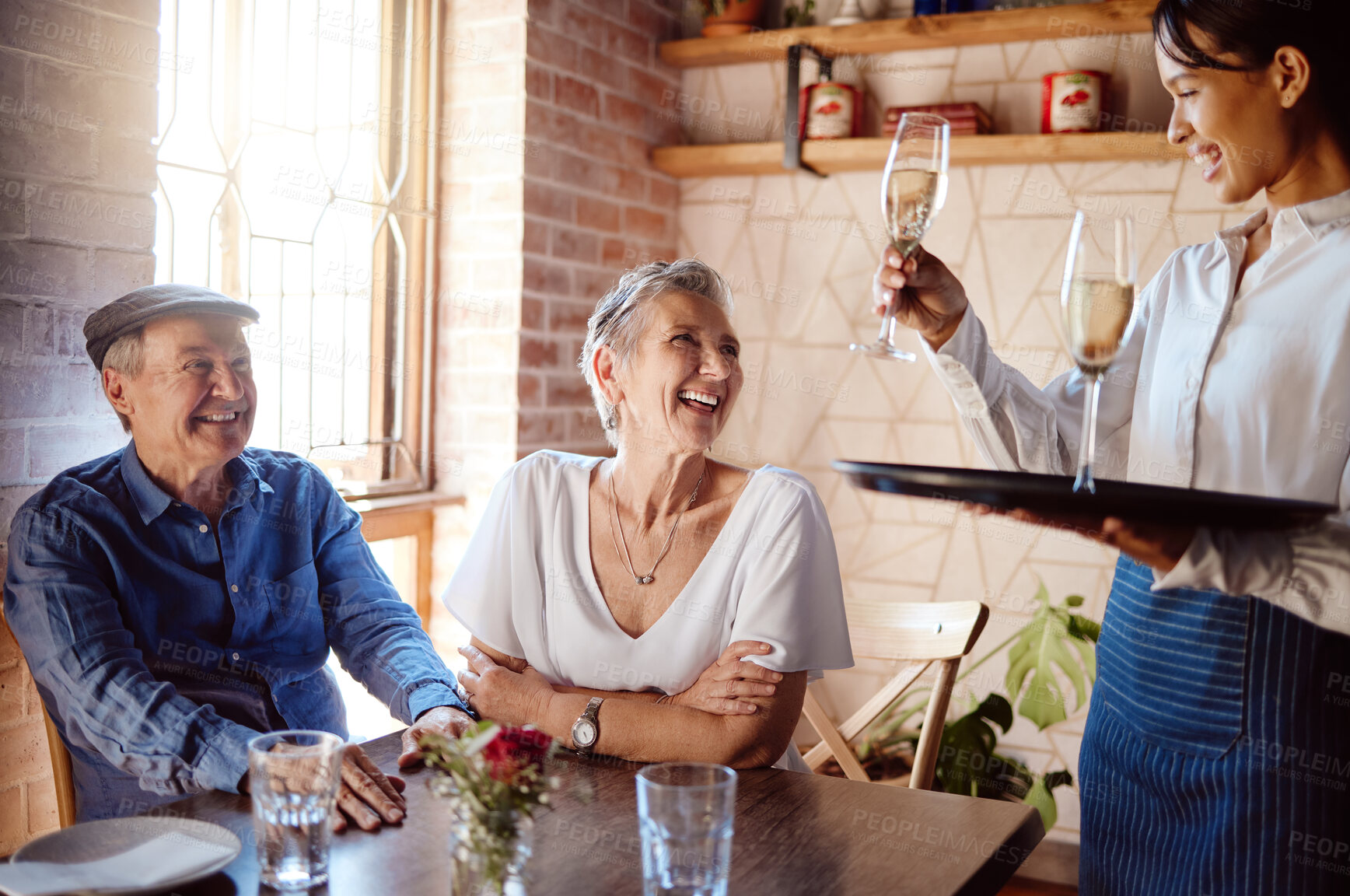 Buy stock photo Senior couple, waiter and champagne in restaurant for wedding anniversary, celebration or birthday. Happy elderly man and woman smile with waitress and serve alcohol to celebrate retirement event