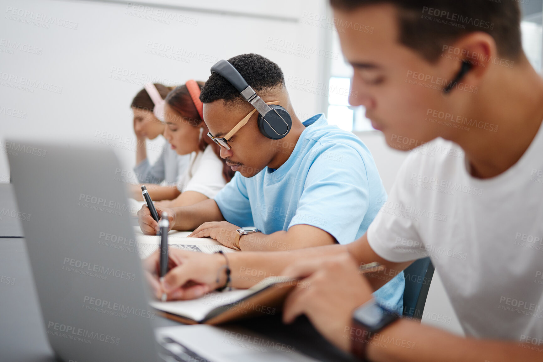 Buy stock photo Student at university study, writing and research for a exam or project with headphones for podcast or music. College, school or education black man learning, scholarship and studying in campus hall