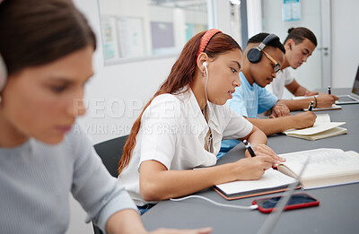Buy stock photo University, headphones and students writing notes while listening to music, educational podcast or radio audio. Earphones, college and group learning, studying or exam preparation with phone on desk.