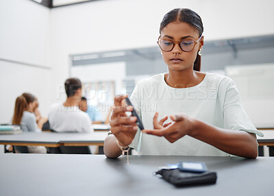 Buy stock photo Diabetes, finger prick and black woman with blood sugar test to check glucose level sitting at desk in class. Sick and diabetic female student using glucometer pen for control and healthcare