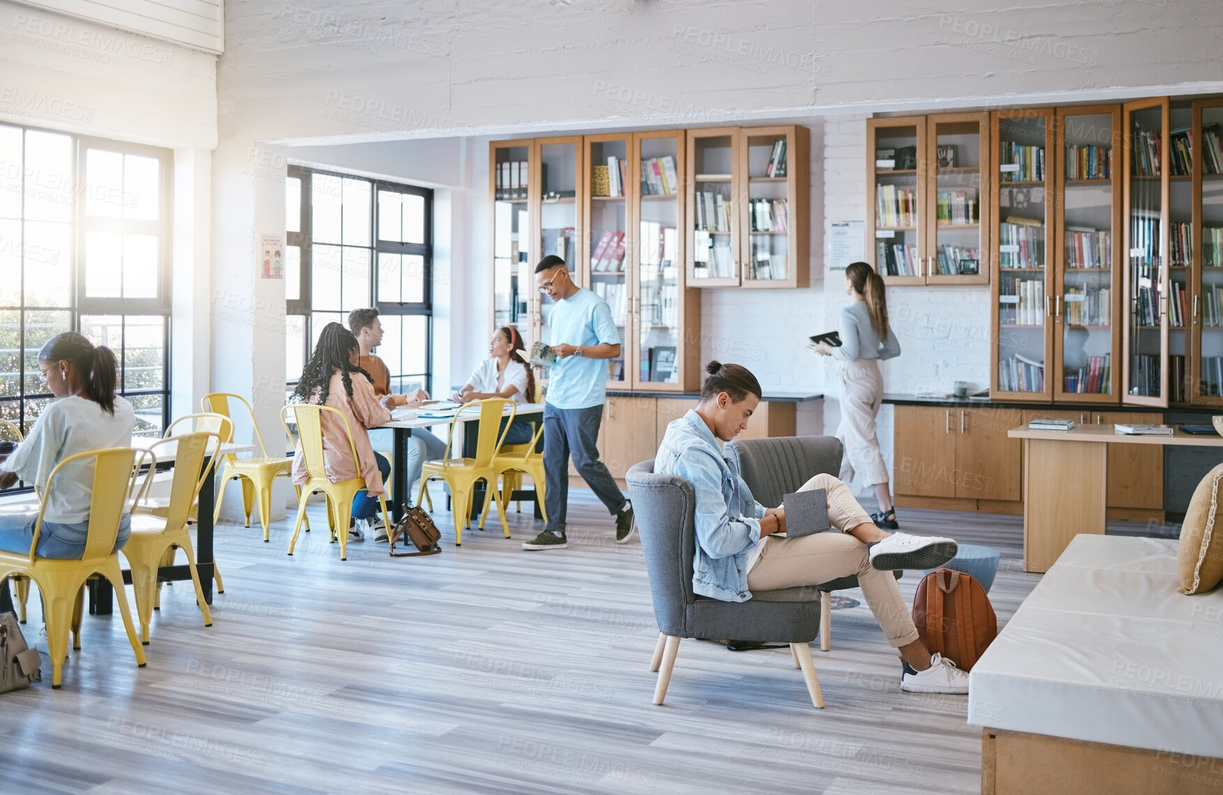 Buy stock photo Education, students and learning in library at university in relax, funky and creative study room. Diversity, college and learners in social space, reading, homework and research with book and pupils