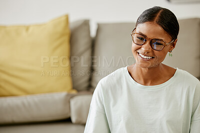 Buy stock photo Home, living room and young Indian woman with smile on face sitting by sofa. Relax, free time and happy girl from India enjoying weekend, holiday and rest in lounge apartment and watching a movie