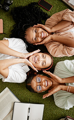 Buy stock photo Students, studying and diversity with happy young women lying together showing smile while at college for education and learning. Top view portrait of female friends on campus or on university grass
