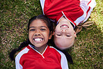 Soccer, sports and children with girl friends lying on a grass field during a football game or match. Kids, training and health with a female child and friend on a pitch for team sport from above