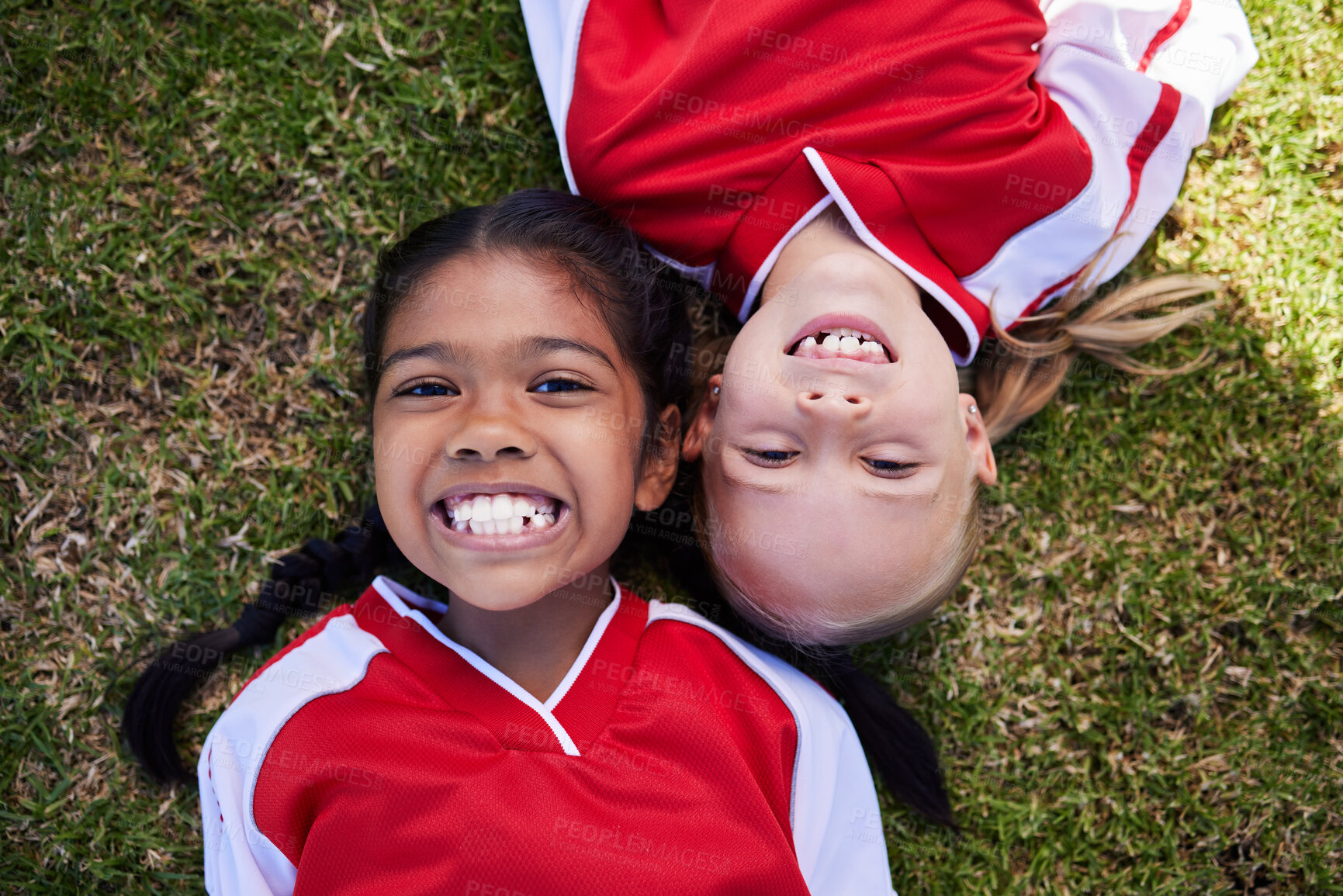 Buy stock photo Soccer, sports and children with girl friends lying on a grass field during a football game or match. Kids, training and health with a female child and friend on a pitch for team sport from above