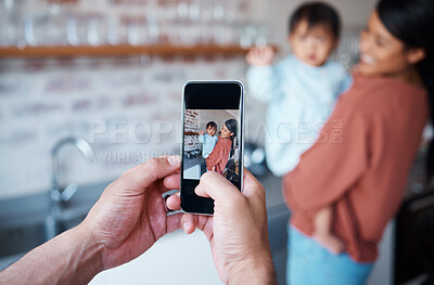 Buy stock photo Father taking a picture of mother and baby on a phone in the kitchen of their family house. Love, care and man taking photo on smartphone of a happy and proud mom bonding with her child in their home