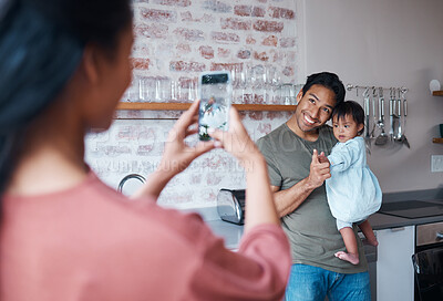Buy stock photo Family, care and mother with phone for photo of father and baby with down syndrome in the living room of their house. Mom taking a picture of a happy dad and child with special needs on a smartphone