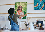 Woman artist, painter and hanging canvas on wall for exhibition to display in studio, art gallery or workshop. Female, lady and creative showing and holding artistic piece and painting in workspace. 