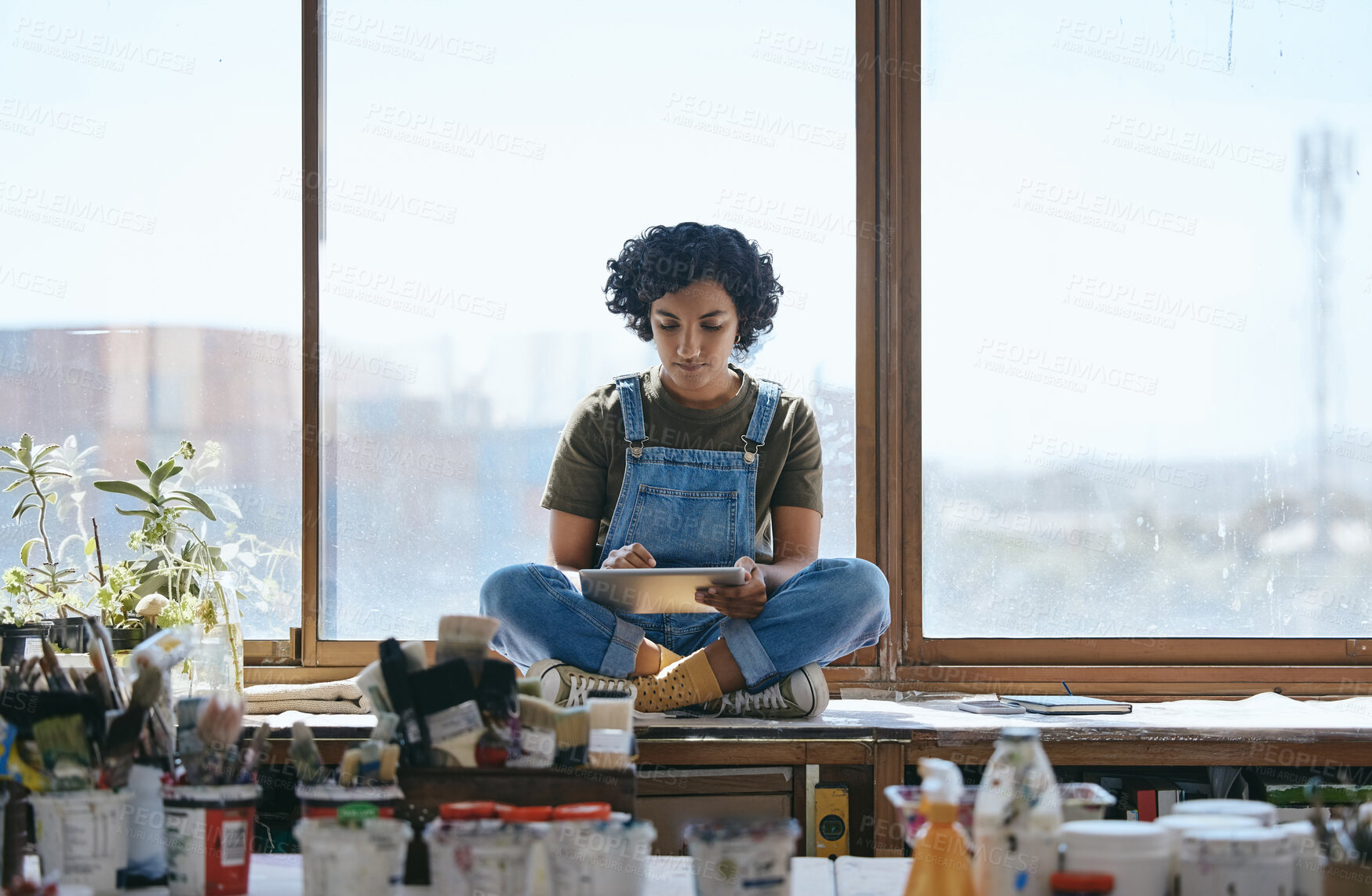 Buy stock photo Creative, art and woman on digital tablet sitting by the window in her studio or workshop. Creativity, artistic and hipster girl artist doing research on the internet with mobile device in workspace.