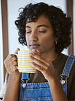 Woman from India with coffee in the morning in her home, drinking and happy. Portrait of girl having a warm drink, breakfast tea and enjoying aroma from coffee cup. Relax, calm and peace before work