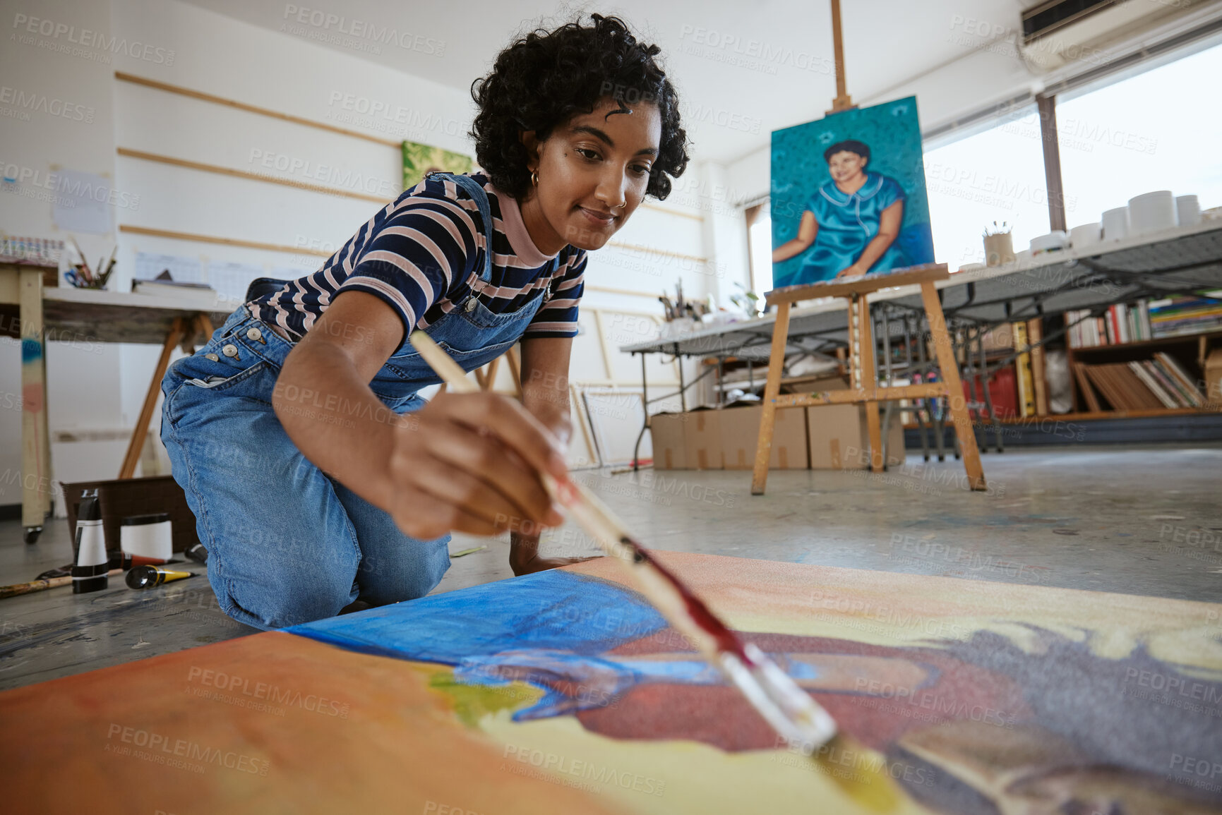 Buy stock photo Studio, art and a woman painting on floor in design school with creativity and paint brush. Artist student from India, happy painter and a girl working on creative school project canvas in classroom.