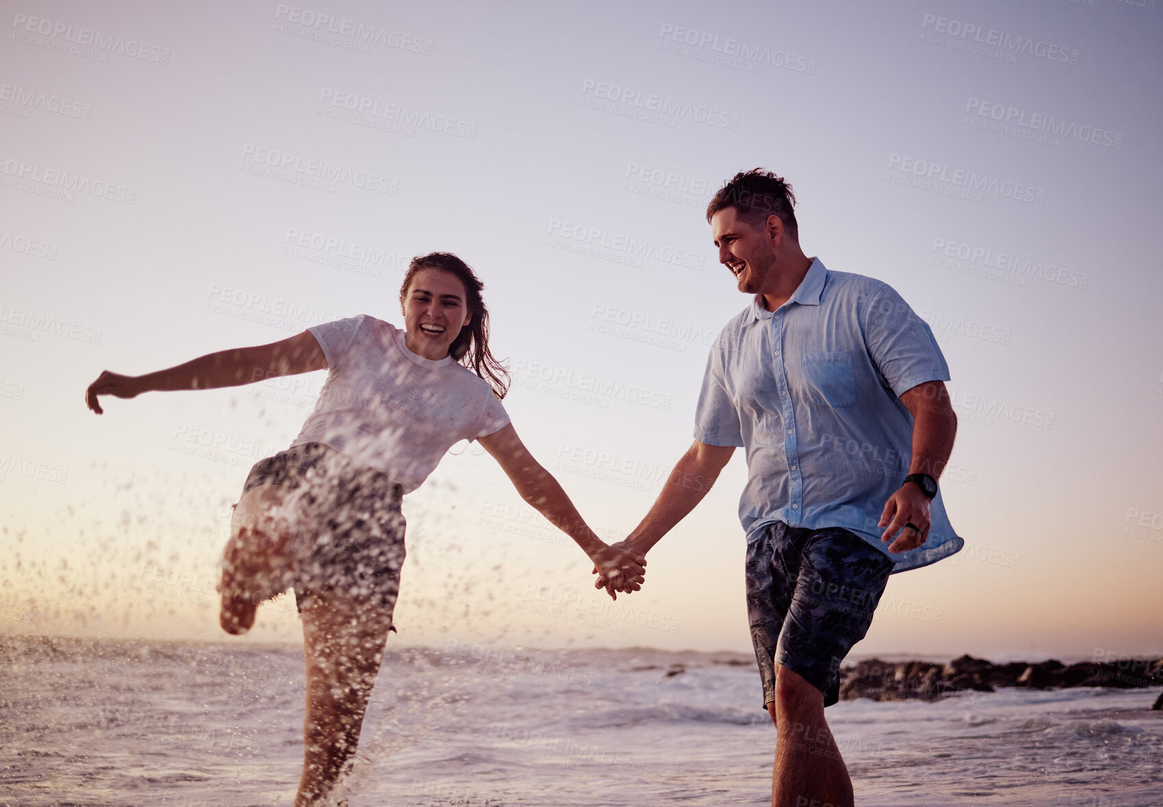 Buy stock photo Beach water splash, couple and happy people together feeling love and fun in summer at sunset. Girlfriend and boyfriend holding hands in the ocean waves and sea on a vacation with quality time