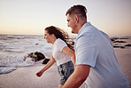 Love, beach and couple holding hands running to the water on a romantic sunset evening together outdoors in nature. Smile, romance and happy woman on honeymoon vacation with an excited partner at sea