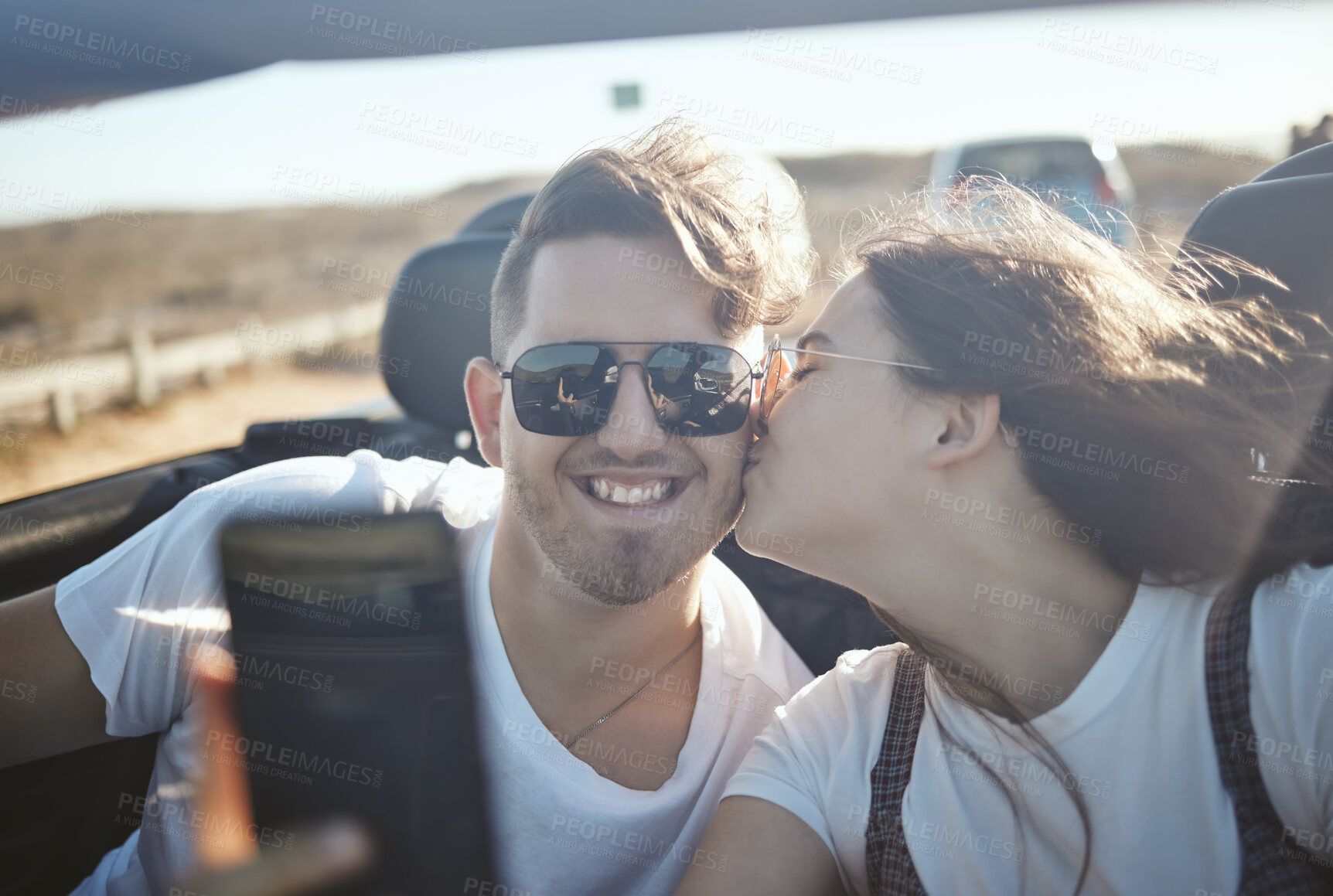 Buy stock photo Selfie, kiss and road trip with a real couple driving on the one road for vacation, honeymoon or romance. Love, happy and kissing with a young man and woman taking a photograph while sitting in a car