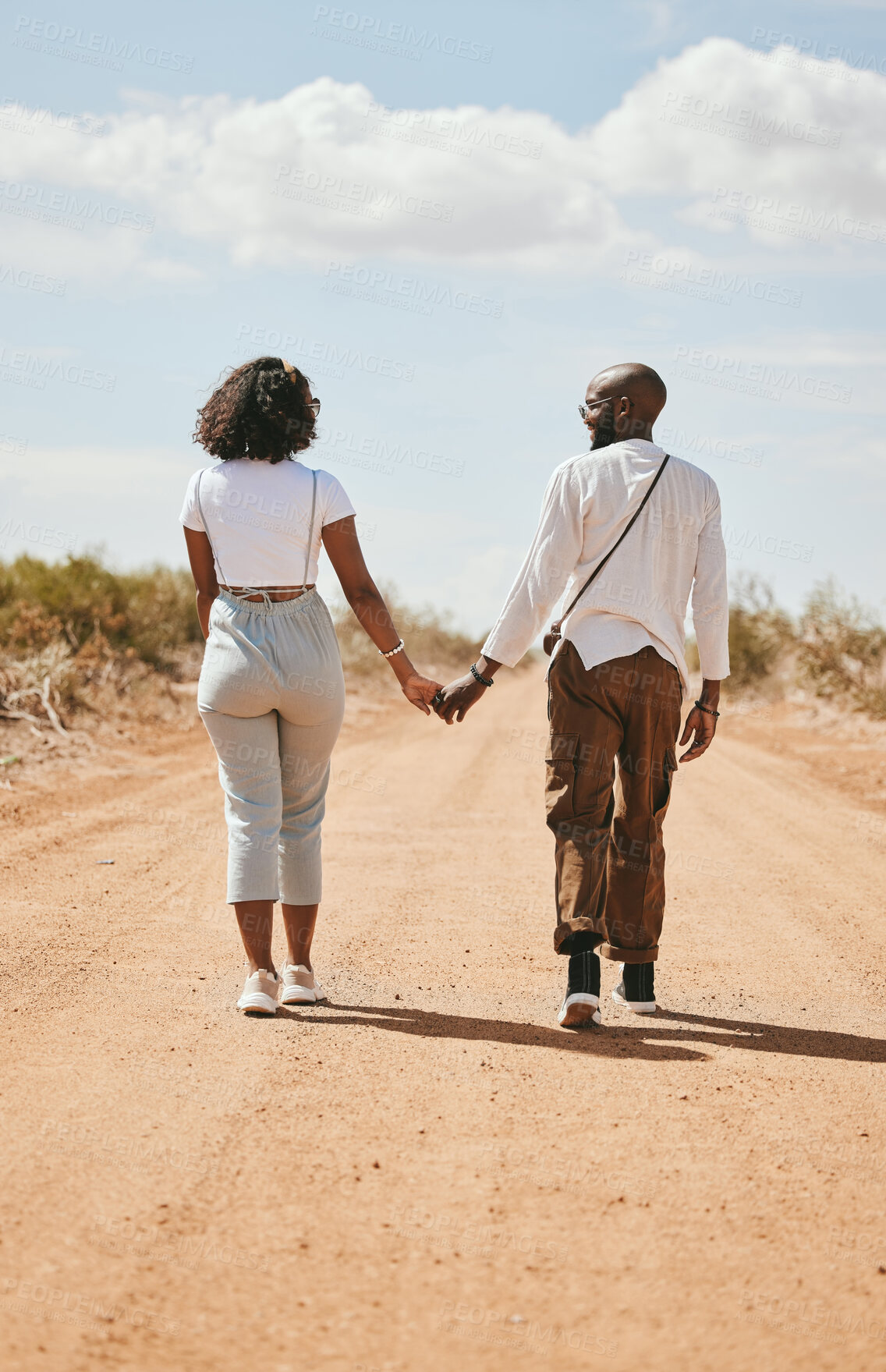 Buy stock photo Black couple, love and holding hands back view in nature walking on vacation on desert, sand or dirt road. Romance, safari and man, woman and bonding, care or spending time together on outdoors date.
