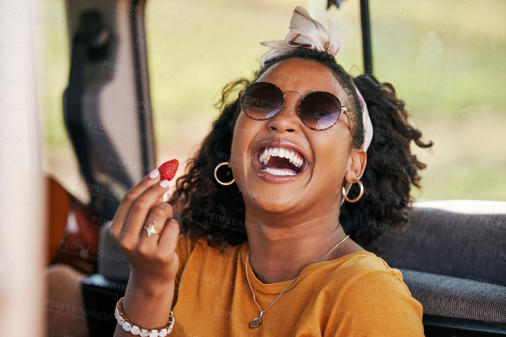 Buy stock photo Happy, road trip and black woman eating a strawberry in a car on a travel holiday in nature. Portrait of a young, funny and African girl with fruit in a van on vacation for adventure and freedom