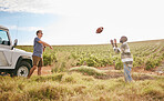 Friends on a trip, travel and play football in nature on field in countryside. Fun, care free men playing together and relaxation on holiday break for bonding in serene landscape in summer.  
