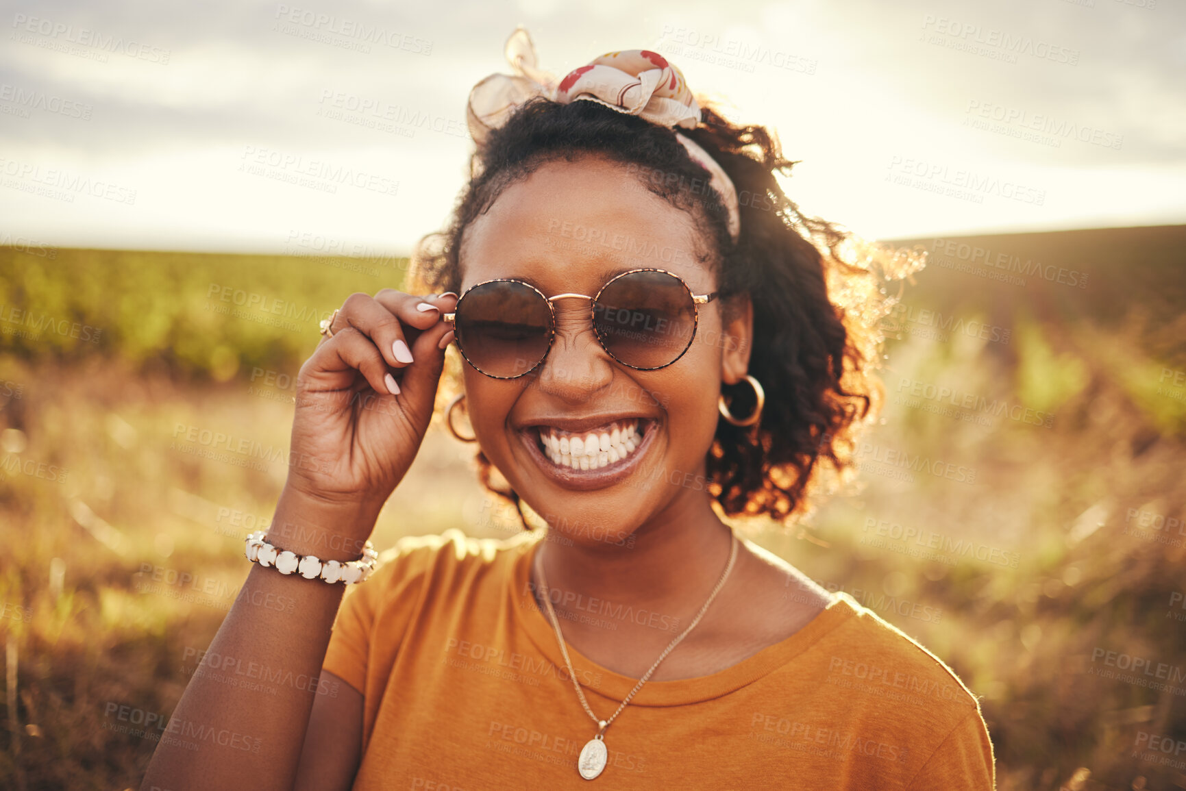 Buy stock photo Face, fashion and nature with a black woman outdoor on a field with green grass in sunglasses and a smile. Happy, vacation and summer with a young female standing outside against a sky background