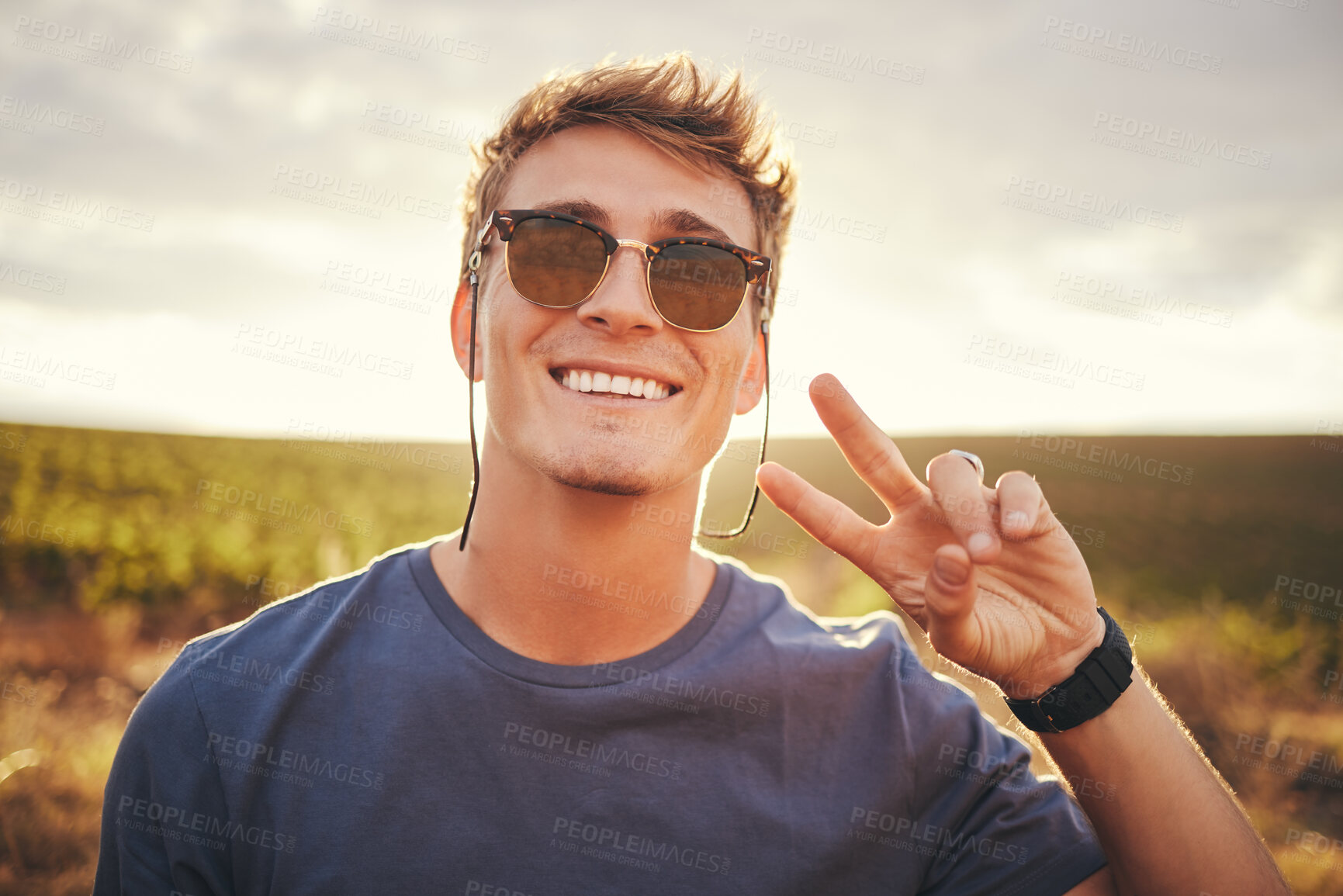 Buy stock photo Nature, hand and peace with a man in a field of green grass with a blue sky or sunset background for travel. Summer, vacation and freedom with a male posing during roadtrip holiday with a hands sign
