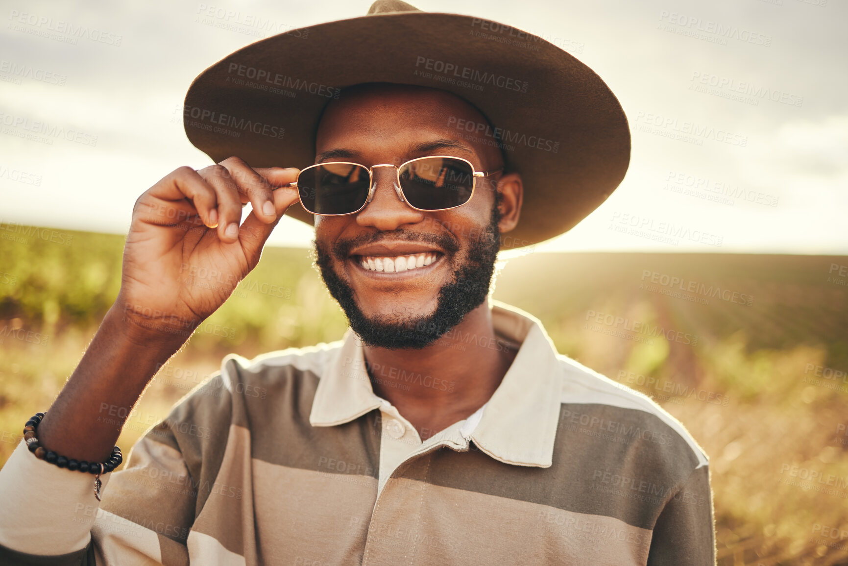 Buy stock photo Black man, sunglasses and farm fashion, holiday vacation and travel with fresh look, cool and relax on road trip. Young male, wear hat and happy smile, adventure and getaway during summer break.