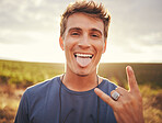 Man, hands and portrait of rock sign for travel tour or vacation in the countryside and nature outdoors. Happy, excited young male traveler, rocker or musician with hand gesture and tongue out