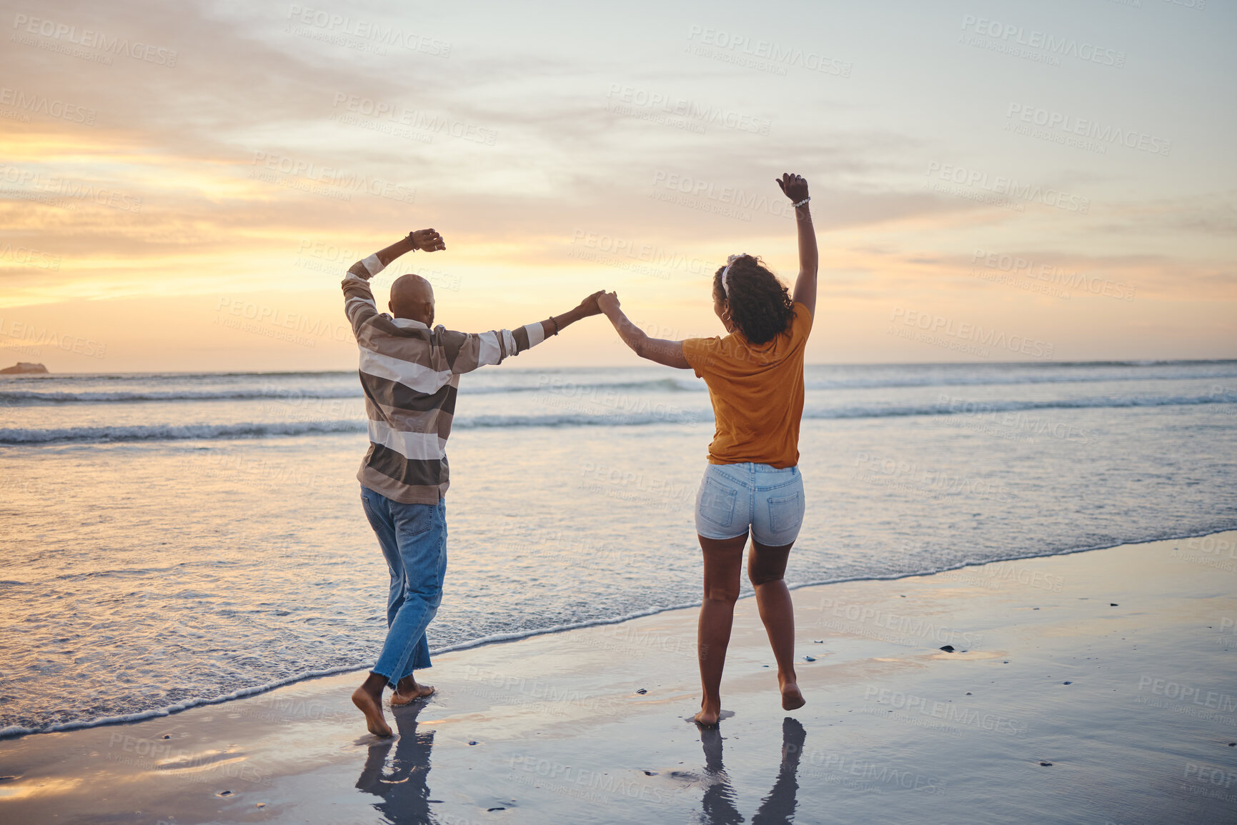 Buy stock photo Love, travel and happy couple at beach enjoying summer vacation or fun honeymoon at sunset while holding hands and being playful. Laughing, energy and seaside holiday with black man and woman at sea