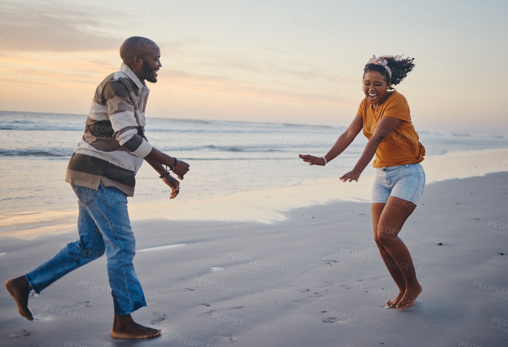 Buy stock photo Love, freedom and couple at a beach at sunset, laughing and having fun on summer vacation in nature. Relax, sea and black woman and man being playful and joking, enjoying sand and ocean walk together