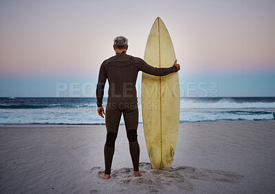 Buy stock photo Surf, sea and sport with a man on the beach with his surfboard looking at the ocean view or horizon at sunset. Health, fitness and sports with a male athlete standing in the sea by water in nature