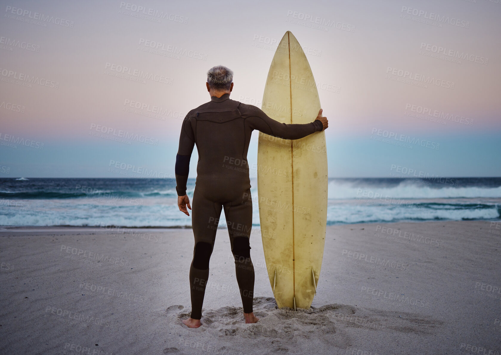 Buy stock photo Surf, sea and sport with a man on the beach with his surfboard looking at the ocean view or horizon at sunset. Health, fitness and sports with a male athlete standing in the sea by water in nature