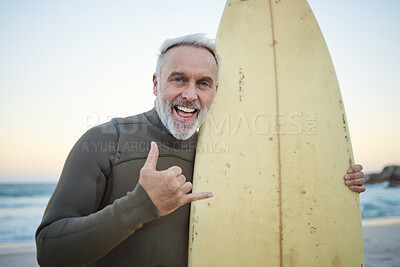 Buy stock photo Senior man, with surfboard and at beach smile, happy and at sunset with swimwear on a holiday and vacation. Portrait, shaka and older male surfer, hand sign and at seaside surfing while on a trip.
