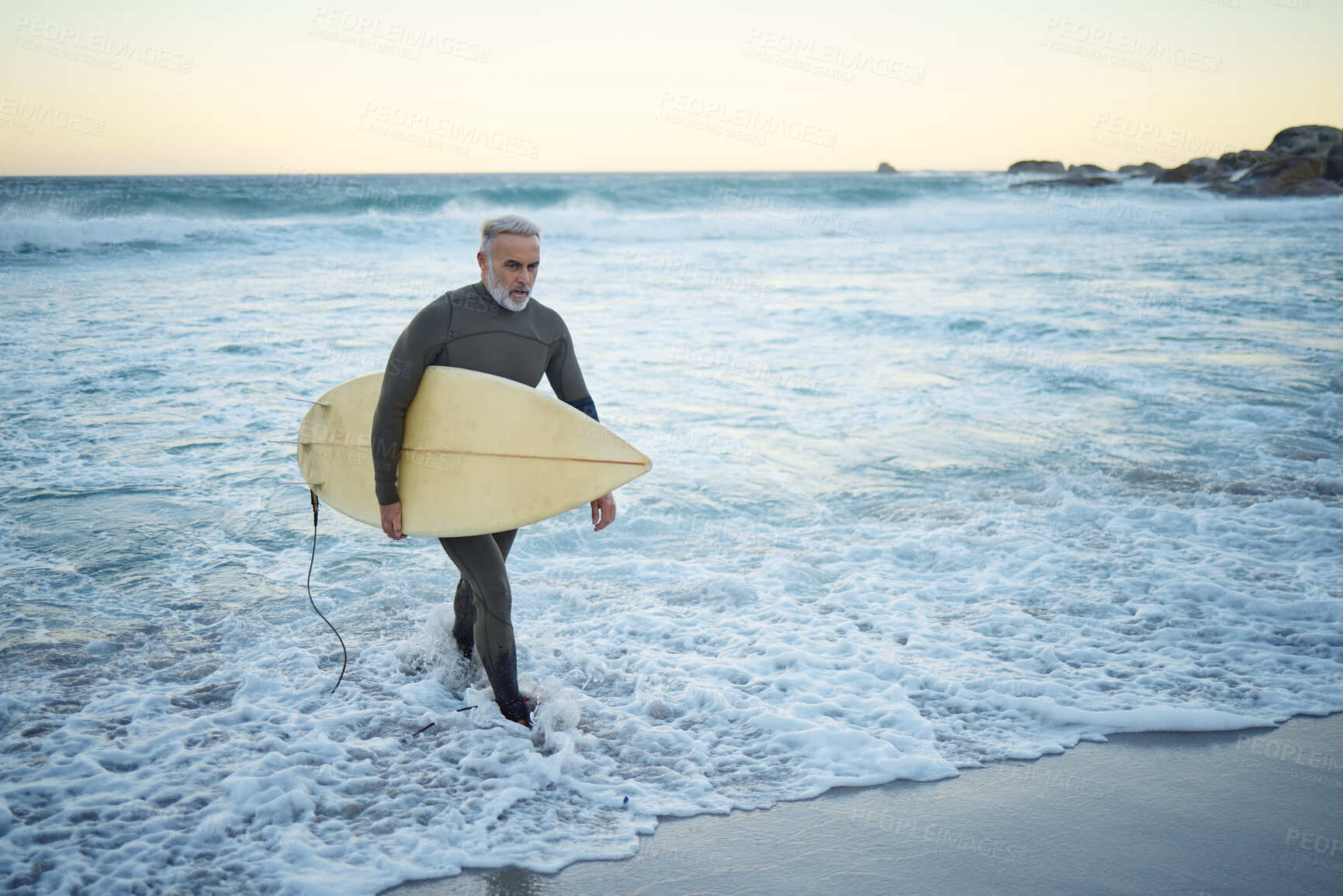 Buy stock photo Surfing, surfboard and senior man on beach for water sports while walking on adventure after riding sea waves on a overcast day. Surfer male at ocean for surf journey or travel vacation in Bali