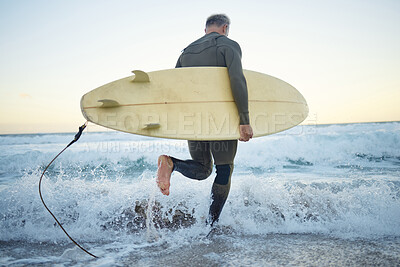 Buy stock photo Man is at the beach in summer, with surfboard while in the ocean waves for sport and fitness during sunrise. Mature surfer while running, in a wet suit to surf and enjoy the sea water for health. 