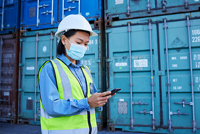 Buy stock photo Covid, social media and logistics worker reading chat on a phone working at a container factory. Asian industrial employee with face mask on web for shipping and delivery of cargo on mobile at a site