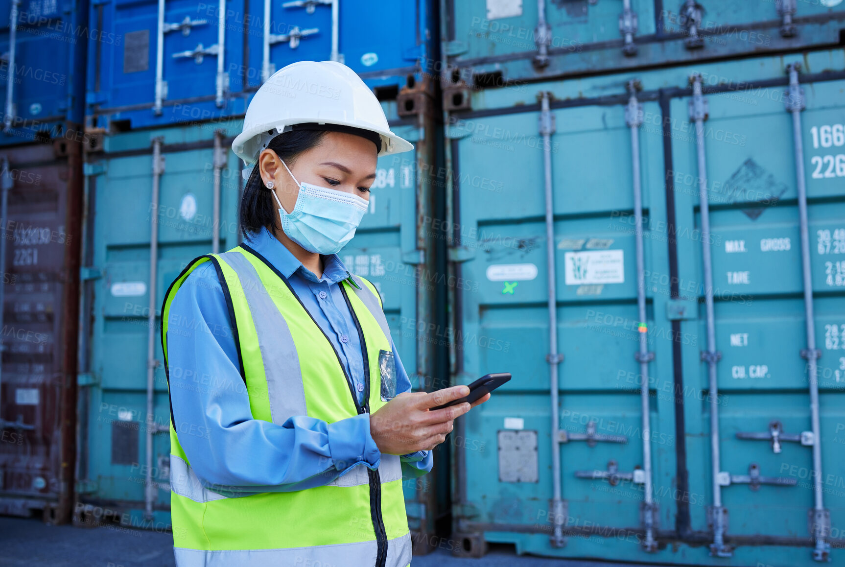 Buy stock photo Covid, social media and logistics worker reading chat on a phone working at a container factory. Asian industrial employee with face mask on web for shipping and delivery of cargo on mobile at a site