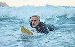 Beach, surfer and old man on surfboard swimming in nature enjoying dangerous water sports and retirement. Training, fitness and senior athlete surfing on the sea waves with freedom in Los Angeles