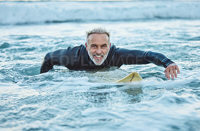 Buy stock photo Senior man, water and sports surfer on a beach with smile training for fitness and health or hobby in the outdoors. Elderly male paddling on surfboard for healthy exercise in the ocean waves at sea