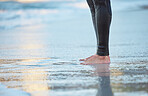 Surf, water and legs of man on the beach for fun adventure, fitness and exercise workout in Rio de Janeiro Brazil. Sand, wellness peace and feet of surfer with wetsuit for sports surfing in ocean sea
