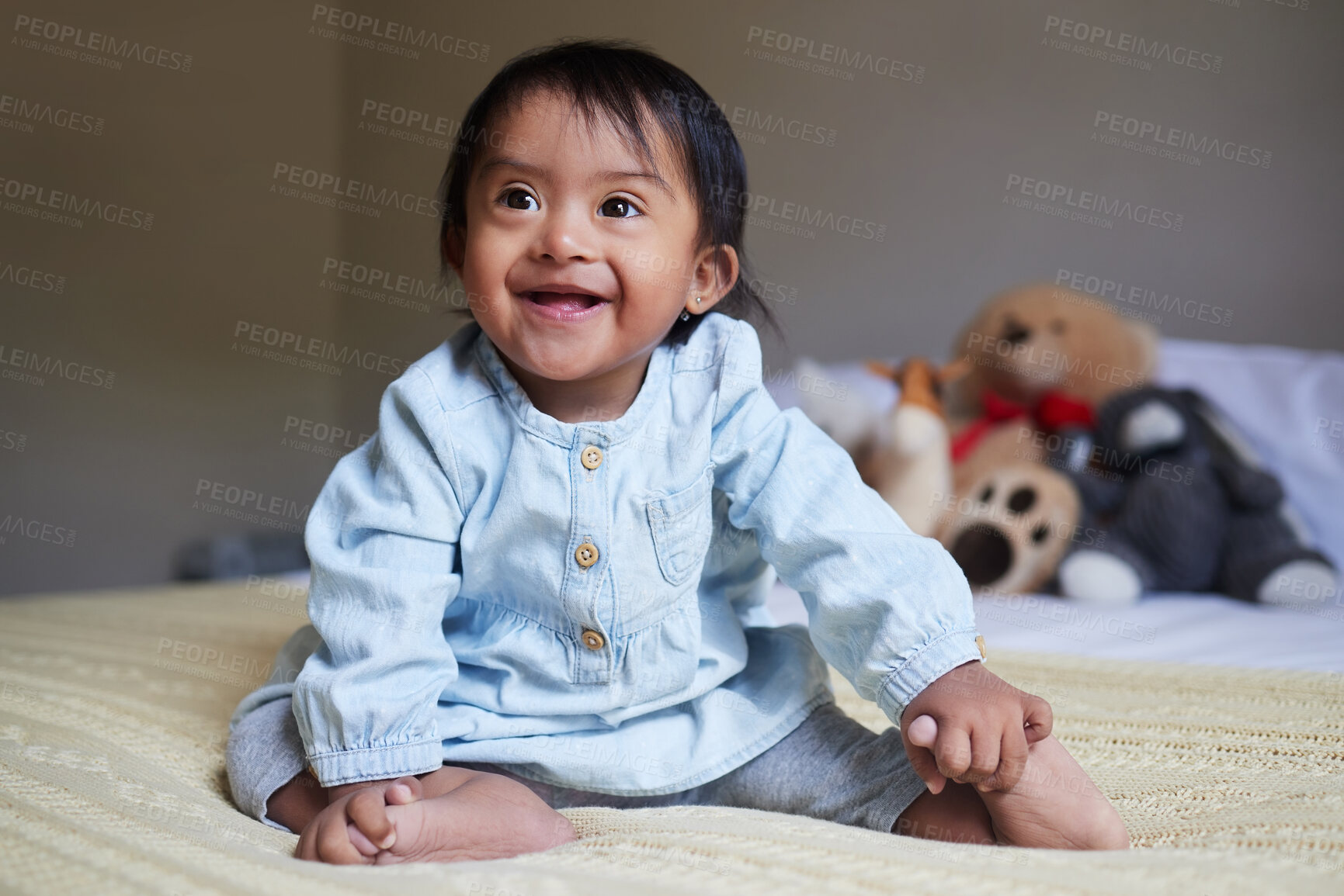 Buy stock photo Baby, down syndrome and special needs child happy with a smile sitting on a bed to relax, be curious and playful in bedroom at home. Cheerful girl with intellectual disability and developmental delay