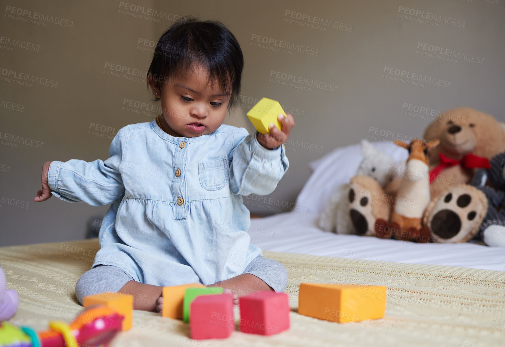 Buy stock photo Down syndrome, daycare and baby on the bed with toys, playing with color shapes and blocks. Child development, special needs and cute girl in bedroom learning, having fun and therapy games for kids 