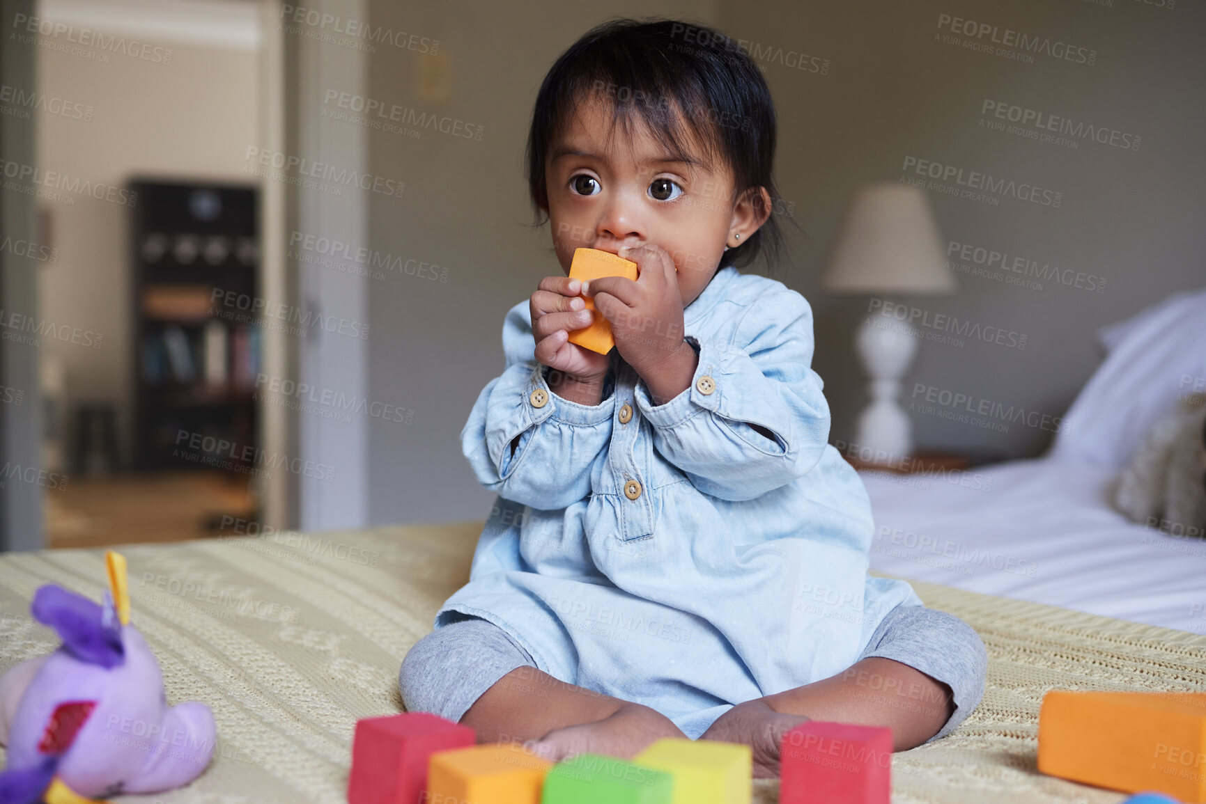 Buy stock photo Down syndrome, baby and with colorful toys, happy or being playful in bedroom at home. Child development, disability and kid or toddler playing with building blocks relax, daycare learning and on bed