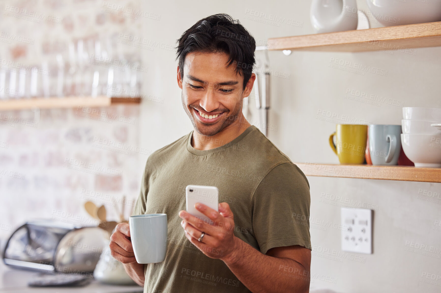 Buy stock photo Phone, coffee and social media with a man in his kitchen in the morning while reading a message in his home. Mobile, internet and tea with a handsome young man sending a text from his house in India 