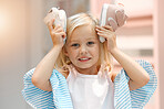 Children, fashion and clothes with shoes in girl hands against her head while shopping in a retail store. Kids, cute and choice with a female child deciding what shoe to buy for her wardrobe