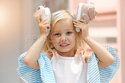 Buy stock photo Children, fashion and clothes with shoes in girl hands against her head while shopping in a retail store. Kids, cute and choice with a female child deciding what shoe to buy for her wardrobe