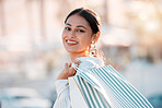 Woman, retail shopping bag and city travel for discount sales, market and fashion promotion in urban Dubai UAE. Portrait of happy, rich wealth and smile young arab girl customer buying luxury outdoor