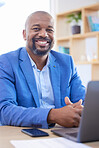 Happy, smile and portrait of an african businessman sitting at his desk and working on a laptop in his office. Happiness, leader and black corporate manager planning management documents on computer.